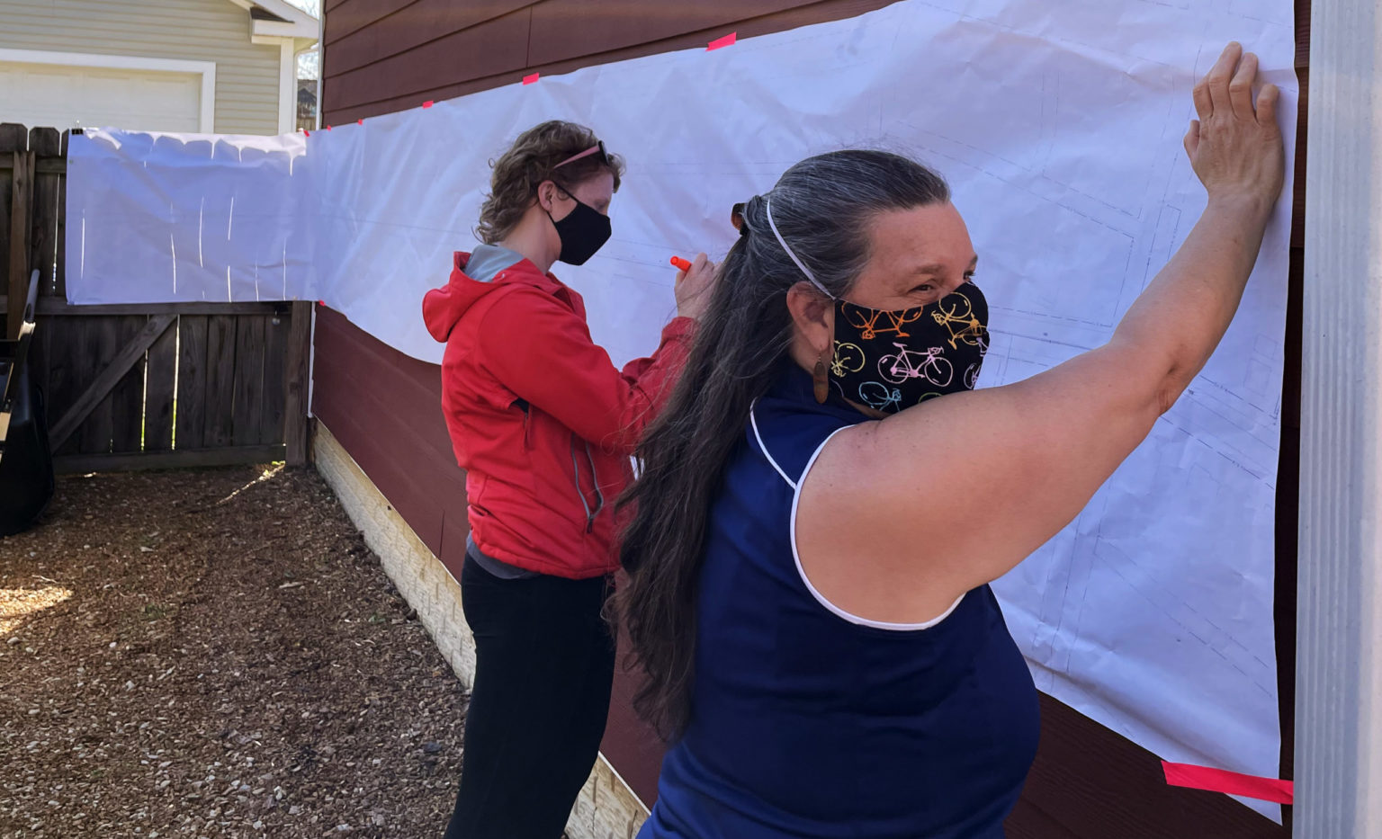 Catherine Girves holding up a long piece of paper against a wall