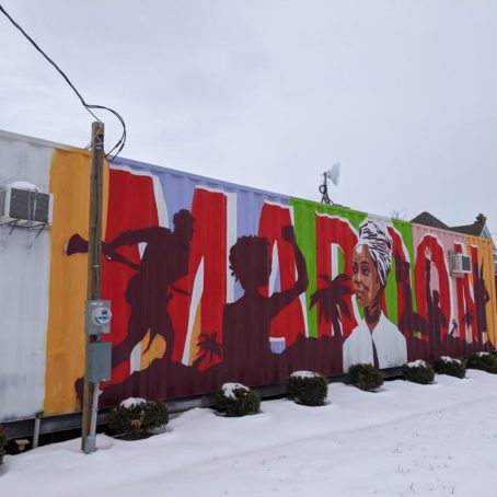 Mural that reads MARION in the background behind a painted Black woman in a white turban.